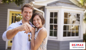 a pair of couple home buyers holding a house key